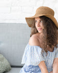 Mujer con sombrero de rafia tejido a crochet de ala ancha en color natural, patrón PDF de verano.