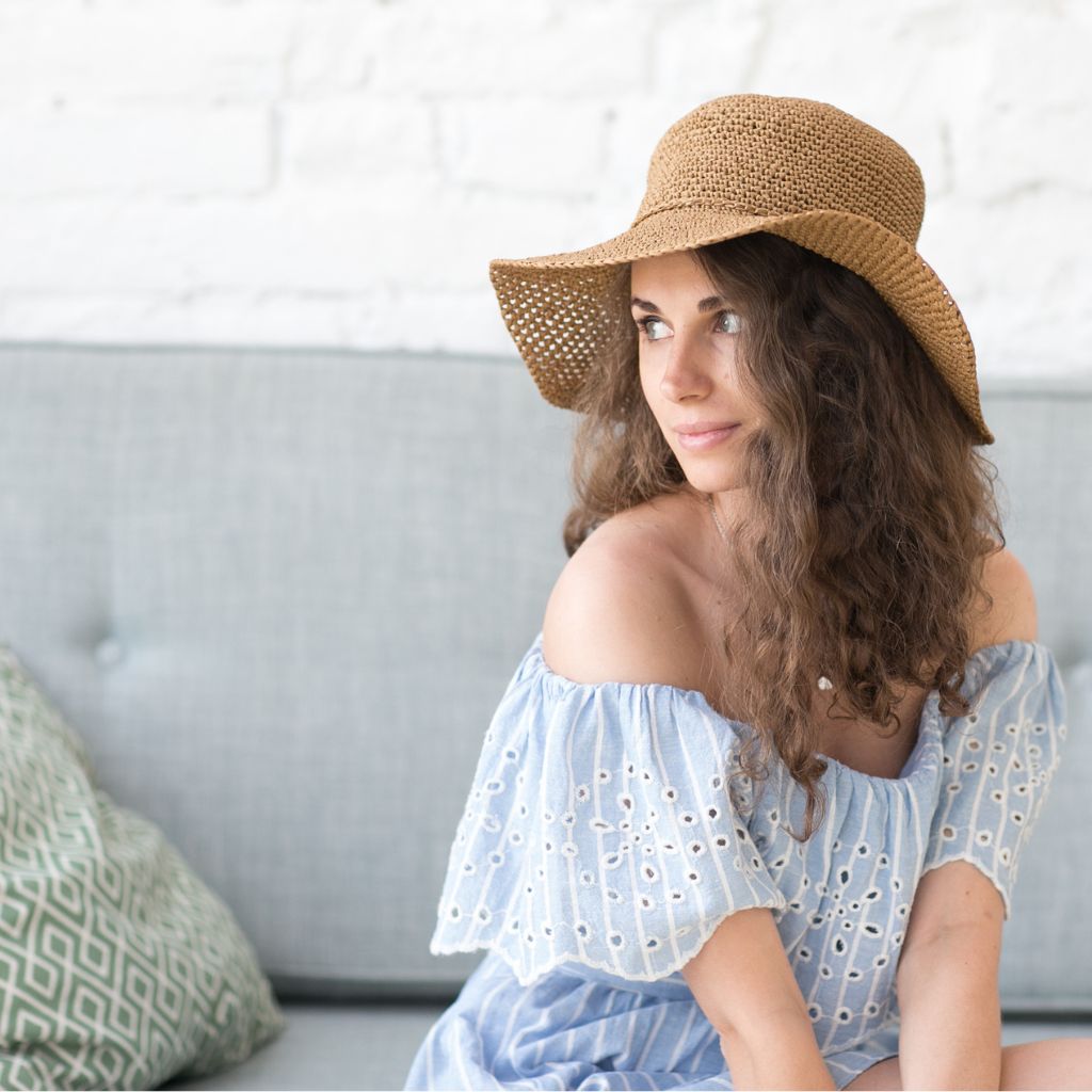 Mujer con sombrero de rafia tejido a crochet de ala ancha en color natural, patrón PDF de verano.